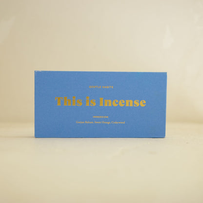 Front view of matte blue Gentle Habits incense box with gold typography on beige background by 9to5 Studios